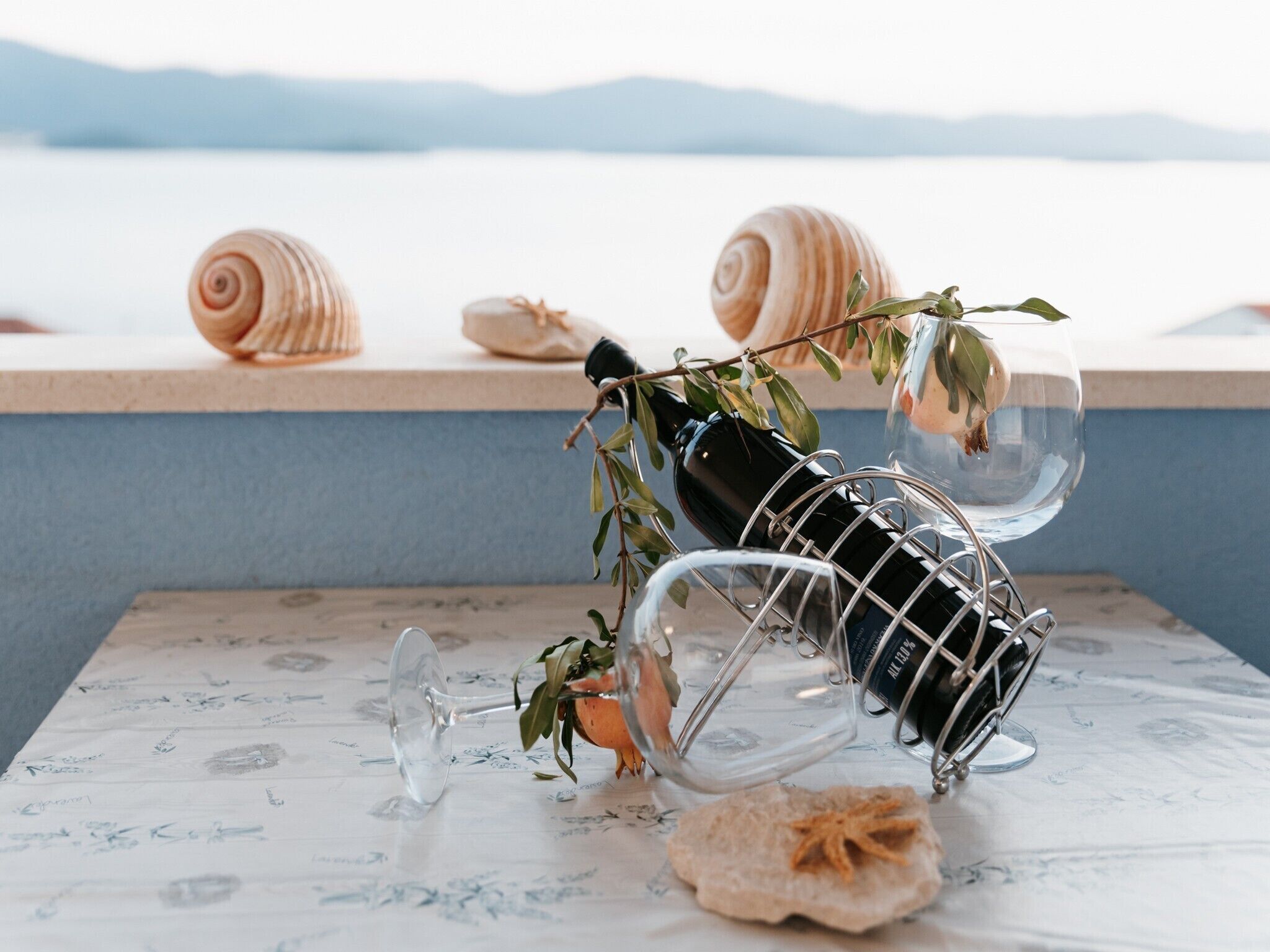 Une bouteille de vin, un verre à vin et un coquillage sur une table, avec vue sur la mer.
