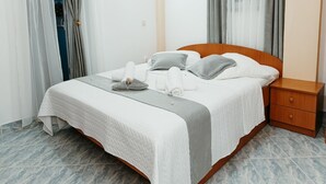 A neatly made bed with a wooden headboard, a bedside table with a drawer, and a wall-mounted light fixture.