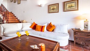 A living room with a white sofa, orange pillows, a wooden coffee table with drinks, and a staircase. - Villa with pool access & BBQ, Albufeira (Albufeira)