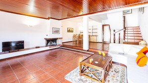 A spacious living room with a fireplace, a television, and a dining area. - Villa with pool access & BBQ, Albufeira (Albufeira)