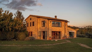 Una casa in pietra a due piani con un ampio portico, un'area pranzo e una cucina a vista.