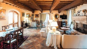 Un'atmosfera tradizionale con travi a vista in legno, un caminetto e un'area pranzo con tavolo e sedie.