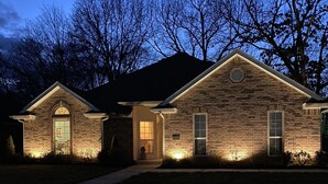 A two-story brick house with a well-lit front porch and a mailbox. - Hot tub, fire pit, great outdoor space, by Coler bike trails, Bentonville Square (Bentonville)