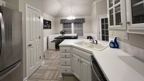 A modern kitchen with white cabinetry, a stainless steel refrigerator, and a built-in dishwasher. - Hot tub, fire pit, great outdoor space, by Coler bike trails, Bentonville Square (Bentonville)