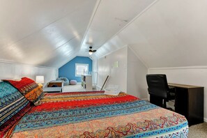 A bedroom with a large bed, a desk, and a chair.