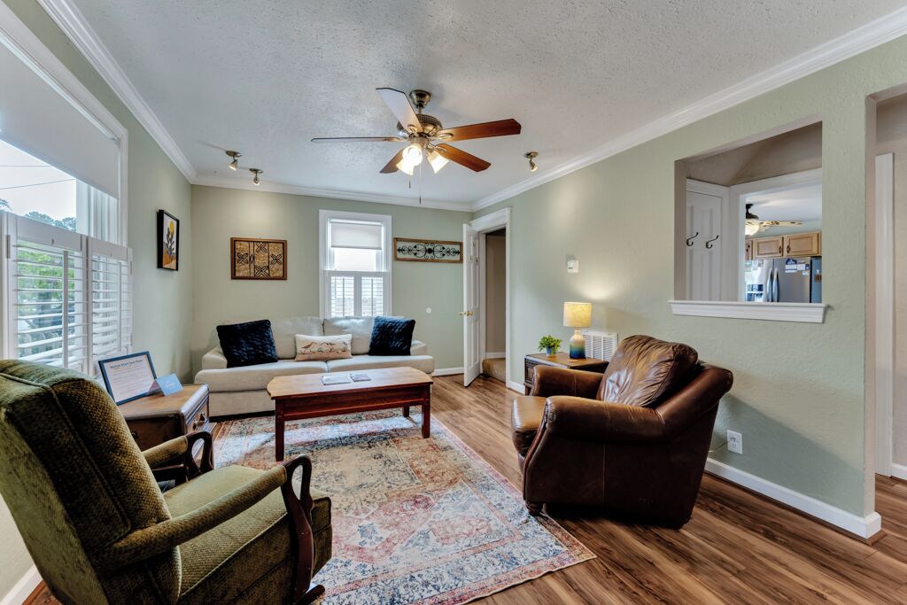 A living room with a ceiling fan, a sofa, a coffee table, and a patterned rug.