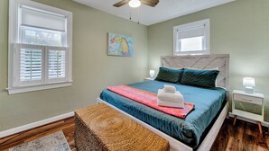 A bedroom with a bed, a ceiling fan, a nightstand, and a window with blinds. - Dog-Friendly Norfolk Cottage Near Ocean View Beach (Norfolk)