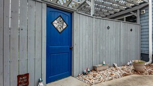 A blue door with a diamond-shaped window, a wooden fence, and a sign that reads "Do Not Piss Off the Gnomes." - Dog-Friendly Norfolk Cottage Near Ocean View Beach (Norfolk)