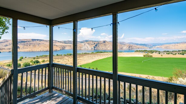 Una terraza de madera con vista a un lago y montañas.