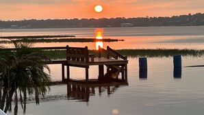 Une jetée en bois s’étendant sur une étendue d’eau calme, avec un coucher de soleil en arrière-plan.