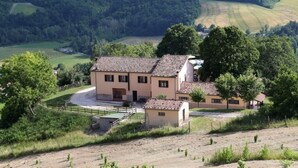 A two-story building with a tiled roof, surrounded by a fenced property with a small pond and a dirt path leading to the entrance. - Villa Eufemia - Country farmhouse with pool (Piano)