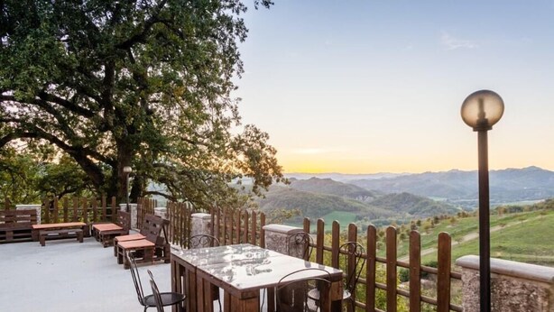An outdoor dining area with a table and chairs, a wooden fence, and a view of the mountains. - Villa Eufemia - Country farmhouse with pool (Piano)