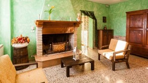 A living room with a fireplace, green walls, a wooden cabinet, and a chandelier. - Villa Eufemia - Country farmhouse with pool (Piano)
