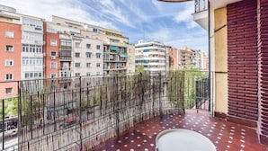 En balkon med udsigt til høje bygninger, et gelænder og flisegulv.