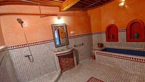 A bathroom with a freestanding bathtub, a sink with a decorative mirror, and a shower area. - Riad Fes Centre (fes)