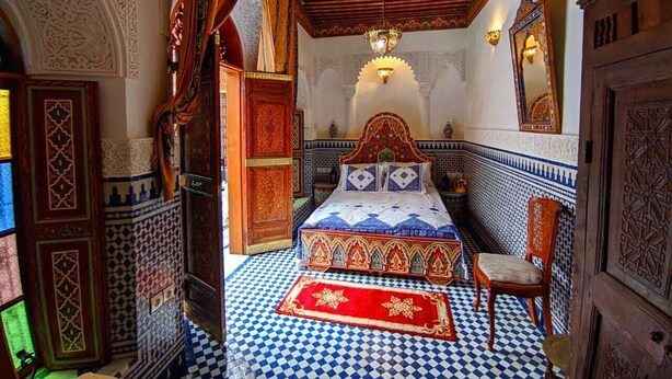 A traditional Moroccan room with a checkered floor, ornate bed, and intricate wall designs. - Riad Fes Centre (fes)