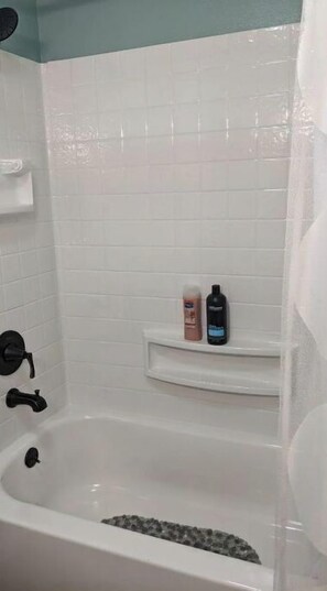 Een bad/douchecombinatie, handdoeken, zeep, shampoo
