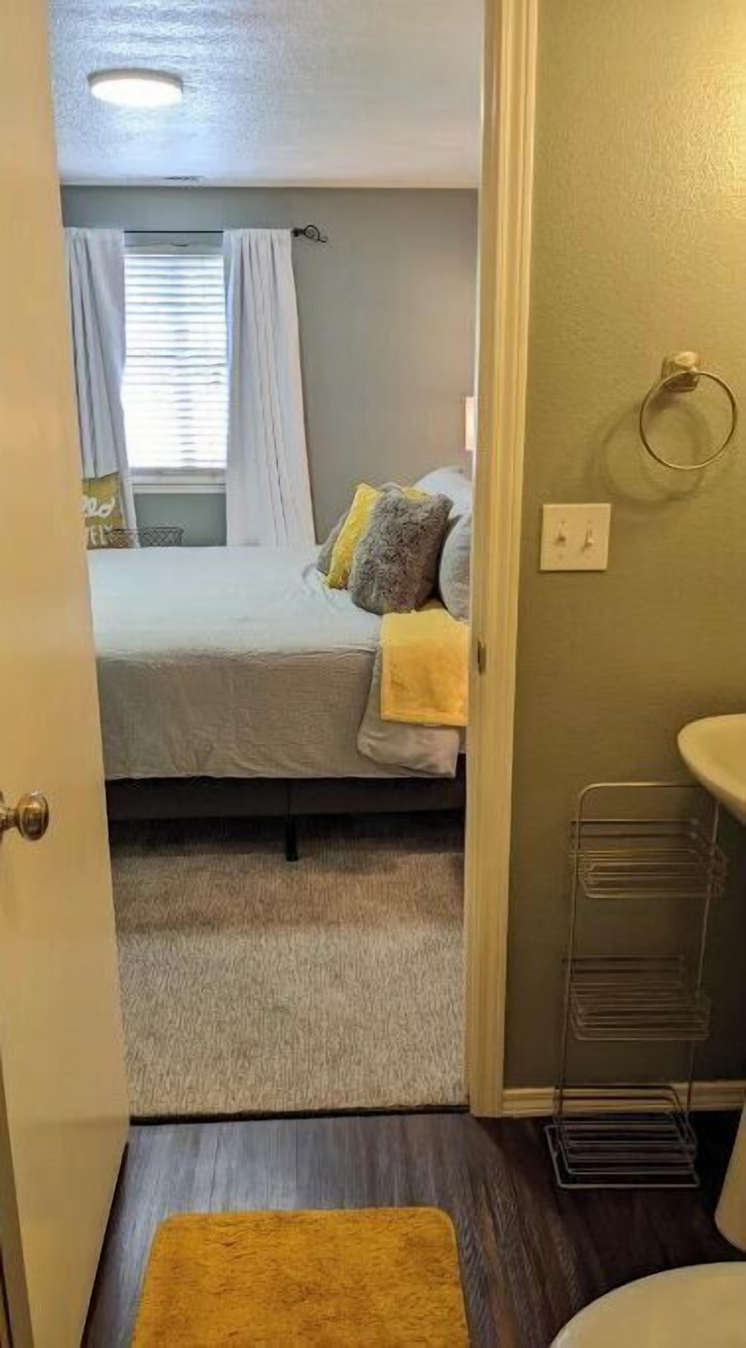 A bedroom with a bed, pillows, a bedside table, and a window with curtains.