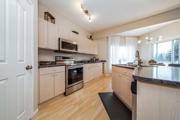 Enjoy cooking in this well-equipped kitchen with a large island, sink, and stainless steel appliances.