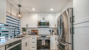 A modern kitchen with white cabinets, stainless steel appliances, and a wooden backsplash. - Ritz Pointe Paradise!  Walking distance to the beach... (Dana Point)