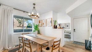 A dining area with a wooden table and chairs, a chandelier, and a view of the outdoors through a window. - Ritz Pointe Paradise!  Walking distance to the beach... (Dana Point)