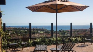 A patio with outdoor seating, a large umbrella, and a view of the ocean. - Ritz Pointe Paradise!  Walking distance to the beach... (Dana Point)