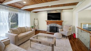 A living room with a wooden ceiling, a fireplace, a sofa, a coffee table, and a TV. - Heavenly Home/Minnetonka Lakes/Nature Scenic View (Minnetonka)