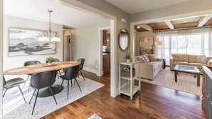 A spacious living area with a wooden dining table, black chairs, a beige sofa, and a coffee table. - Heavenly Home/Minnetonka Lakes/Nature Scenic View (Minnetonka)