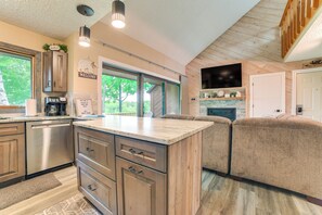 A modern kitchen with a large island, wooden cabinets, a coffee maker, and a view of the outdoors. - Bellaire Ski Condo: 1 Mi to Summit Mountain! (Bellaire)