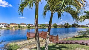 Vista su un lago con un pontile di legno e palme.