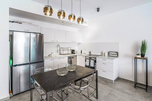 Una cocina moderna con electrodomésticos de acero inoxidable, una mesa de comedor con sillas e iluminación colgante.