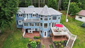 A large, two-story house with a wrap-around porch and a covered outdoor seating area. - Beautiful Waterfront Home in Colton Near Local Colleges (Colton)