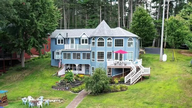 A large, two-story house with a wrap-around porch, a small deck, and a flag. - Beautiful Waterfront Home in Colton Near Local Colleges (Colton)