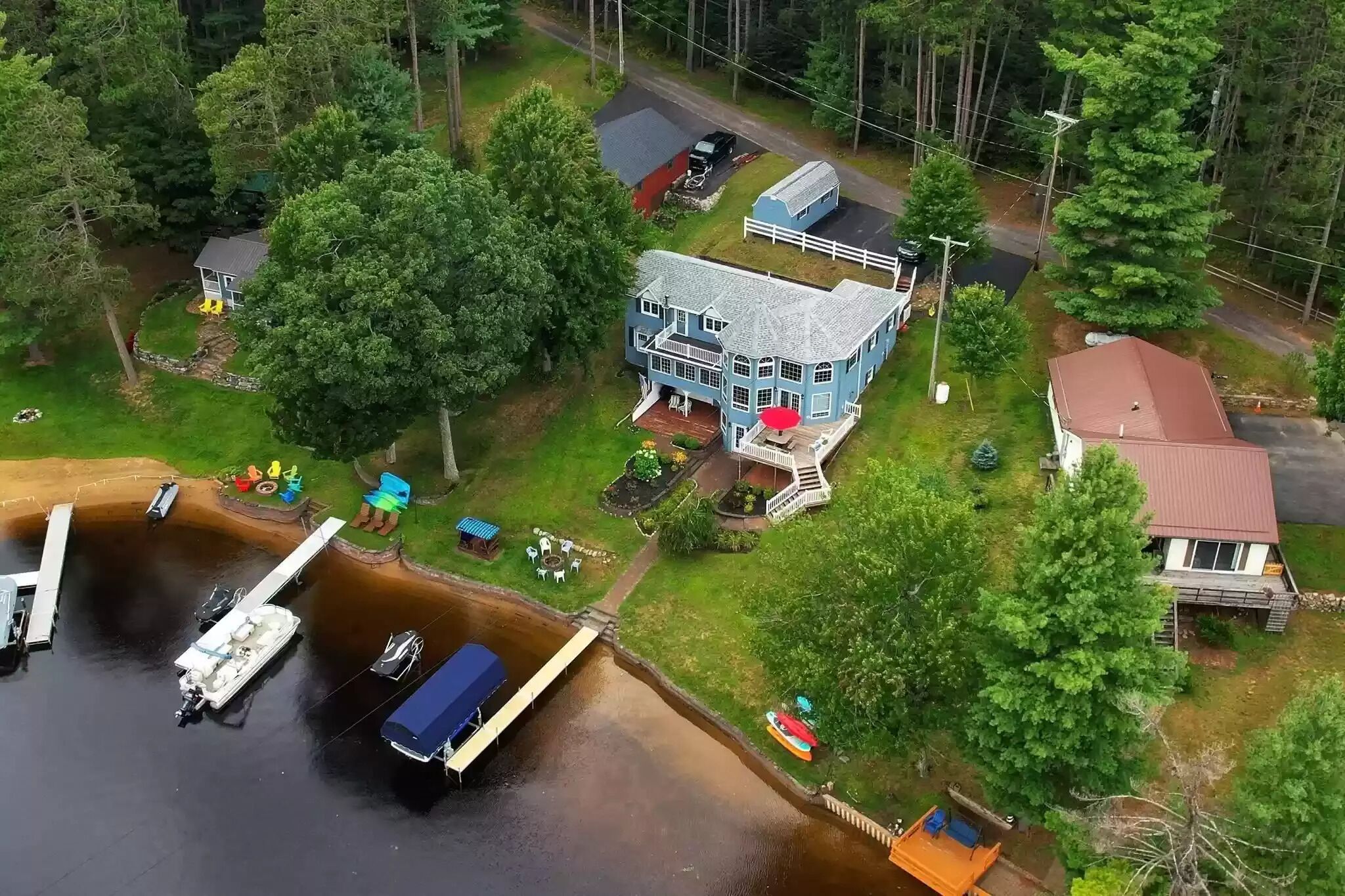 An aerial view of a lakeside property with a large house, dock, and boats.