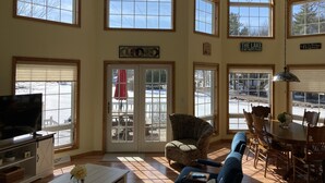A spacious living room with large windows, a television, a sofa, and a dining area with chairs and a table. - Beautiful Waterfront Home in Colton Near Local Colleges (Colton)