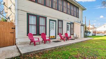A two-story house with a front porch, a wooden fence, and a grassy yard.
