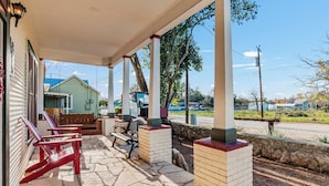 A covered outdoor area with stone flooring, wooden benches, and a view of a road and buildings in the distance. - Carriage Utopia 4 | Pet-Friendly Stay in Bandera (Bandera)