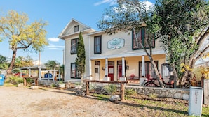 A two-story building with a porch and a sign that reads 'Carriage House Inn.' - Carriage Utopia 4 | Pet-Friendly Stay in Bandera (Bandera)