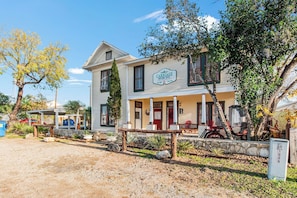 A two-story building with a porch and a sign that reads 'Carriage House Inn.' - Carriage Utopia 4 | Pet-Friendly Stay in Bandera (Bandera)