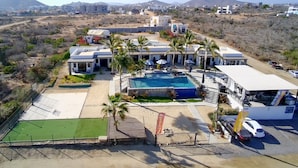 Hotel com piscina, palmeiras e paisagem desértica.