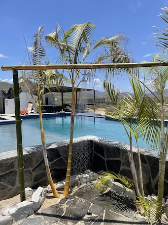 Una piscina al aire libre, sombrillas, sillones reclinables de piscina