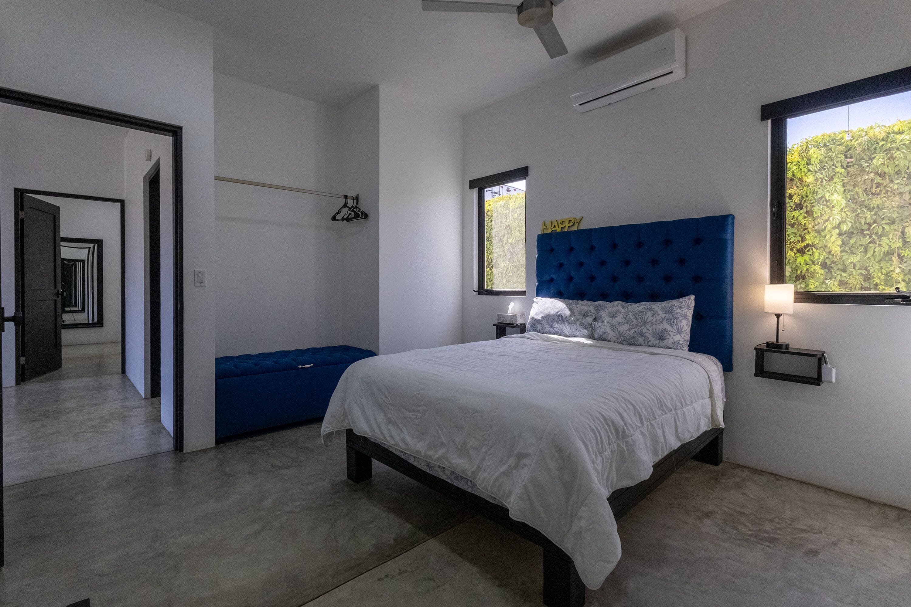 A bedroom with a bed, a window, a ceiling fan, and a wall-mounted nightstand.