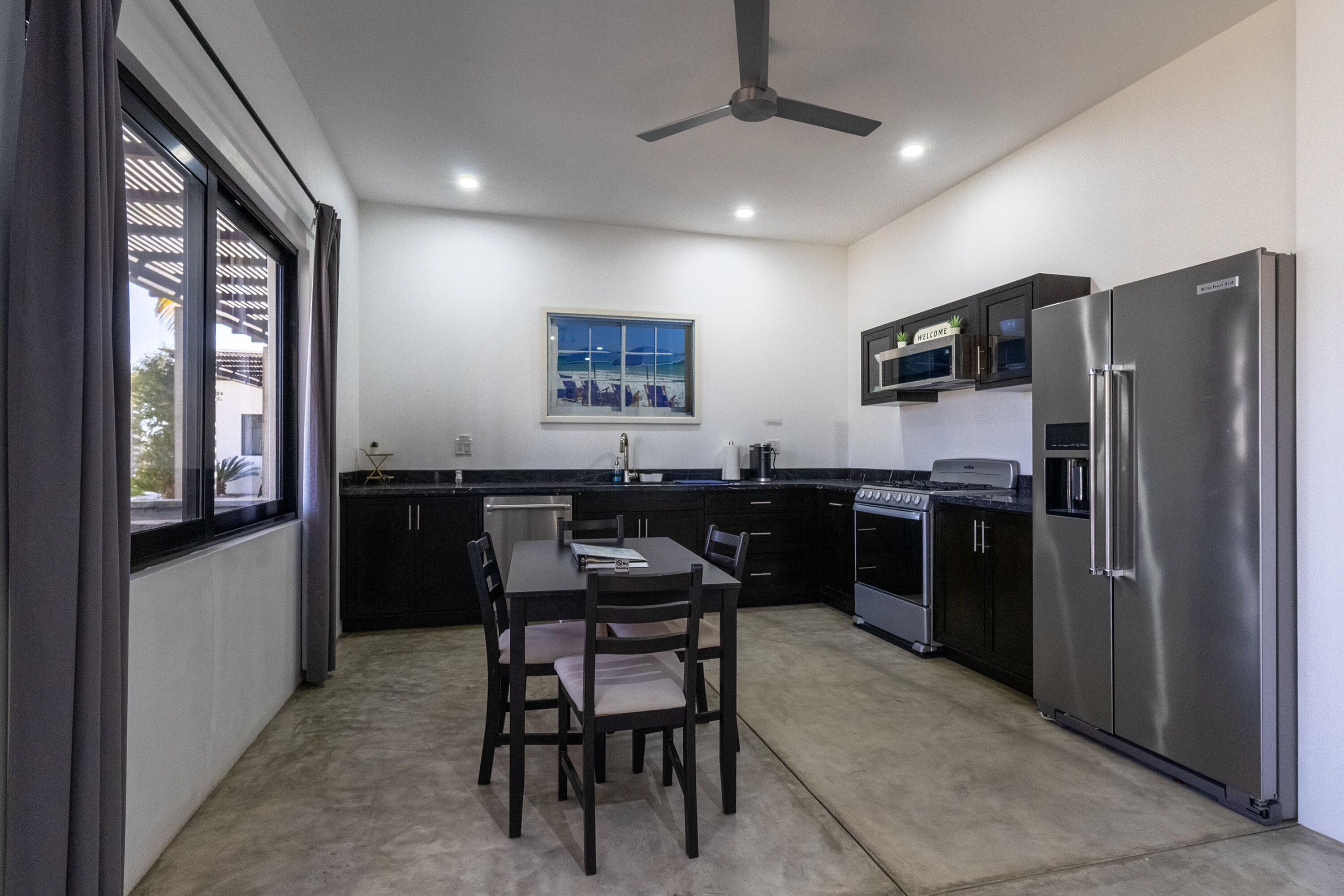A modern kitchen with a dining table, chairs, a refrigerator, and a stove.