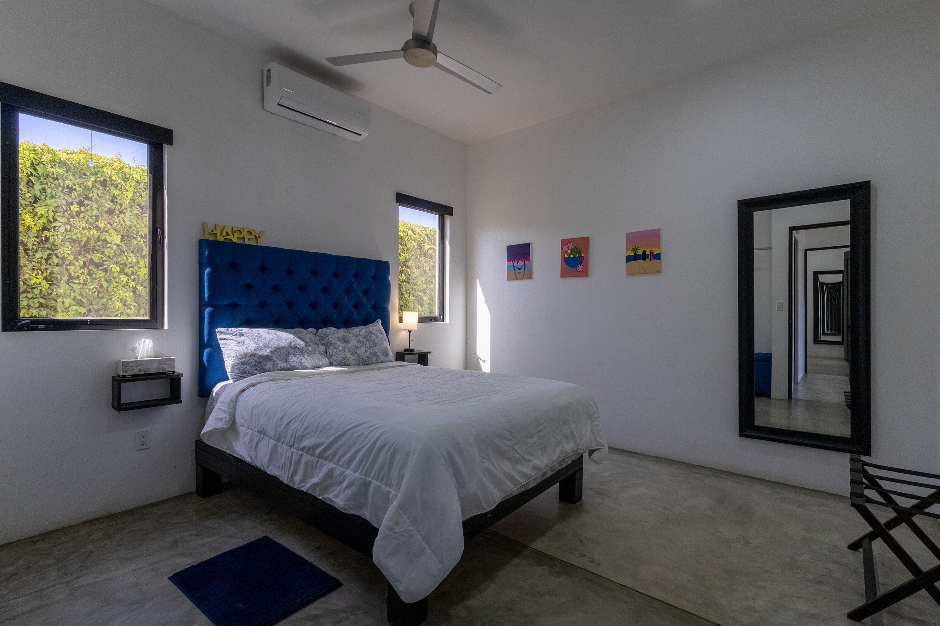 Un dormitorio con cama, ventilador de techo, ventana y espejo.