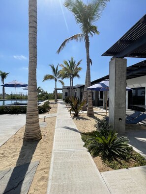 A resort with palm trees, outdoor seating, and a pool. - Las Palmas Hotel (El Pescadero)
