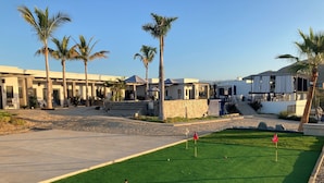 Um campo de golfe com putting green, palmeiras e o hotel Las Palmas Hotel ao fundo.