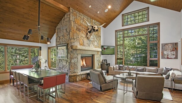 Un salón amplio con chimenea de piedra, ventanas grandes y una zona de estar acogedora.