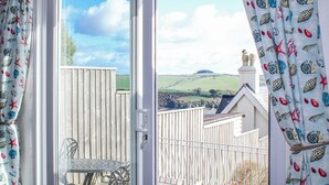 A room with a view of a rural landscape, a white door, and a metal table with chairs. - Waders (Salcombe)