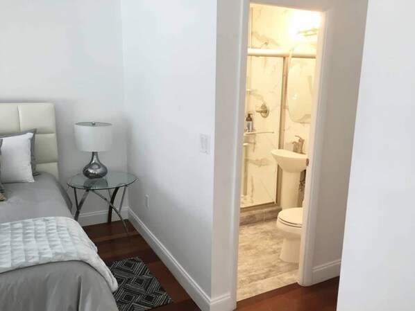 Un dormitorio con cama, una mesita de noche con lámpara y una alfombra pequeña.