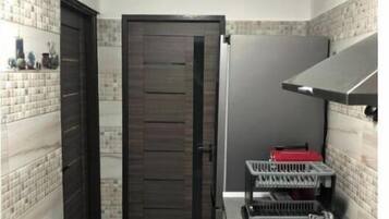 Une cuisine de taille modeste, dotée d’une porte en bois foncé, d’un évier en acier inoxydable et d’une cuisinière à gaz.